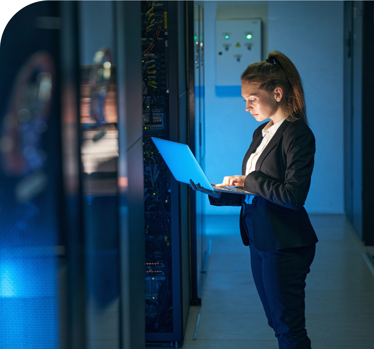 Photo of a lady working on a laptop in a server room