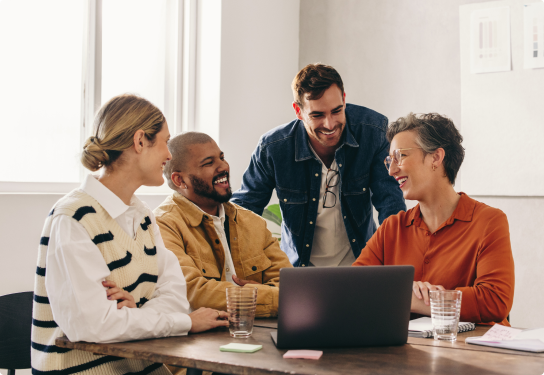 Image of two men and two woman at a table working on a laptop