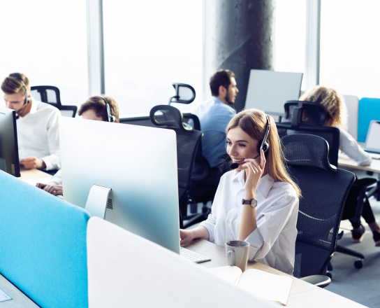 Image of a woman working in a call centre with a colleague beside her wearing headsets