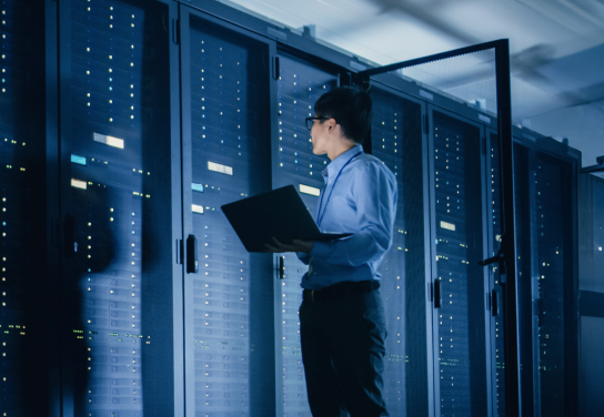 Man walking around working on a laptop in a server room