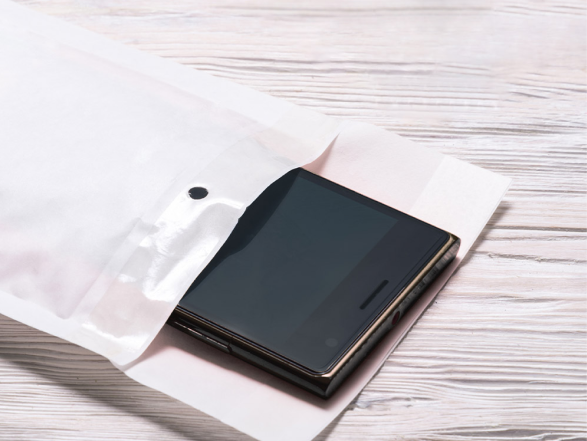 Image of a mobile phone being placed into a postage bag