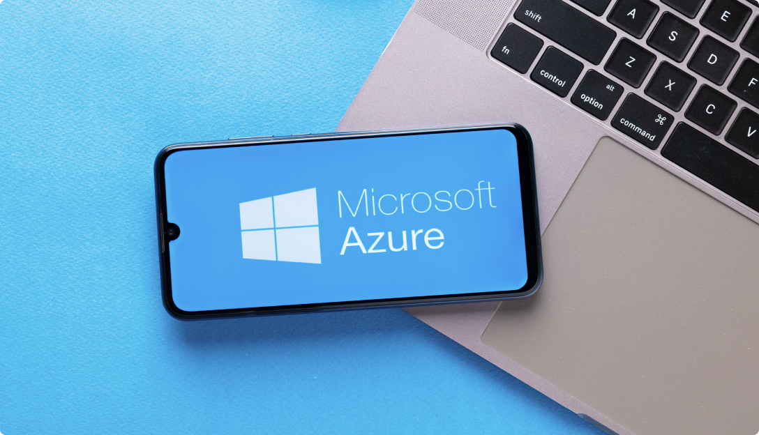 Laptop with a mobile phone sitting on it with the Microsoft Azure logo on the screen