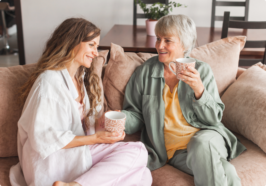 Image of two woman sitting on a sofa having coffee