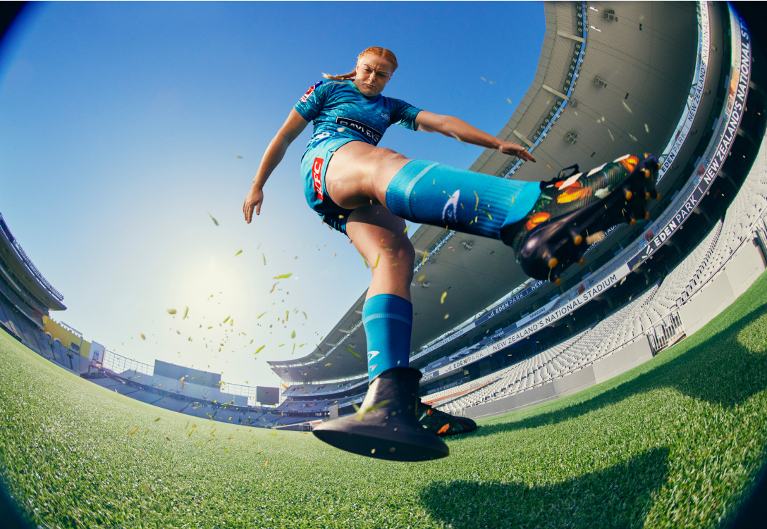 Photo of a woman playing rugby who has just finished kicking the ball