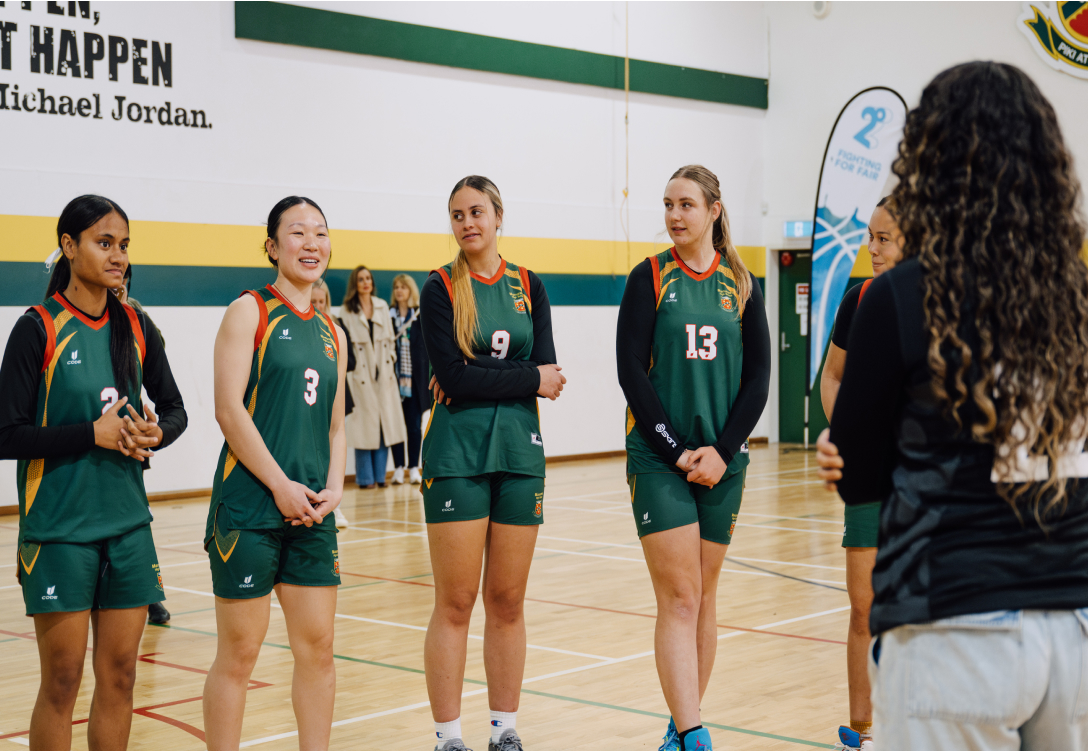 Image of a girls basketball team lined up in front of their coach