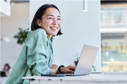 Image of a lady wearing pink glasses working on a laptop