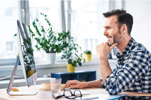 Image of a man looking at his Apple desktop computer in his office