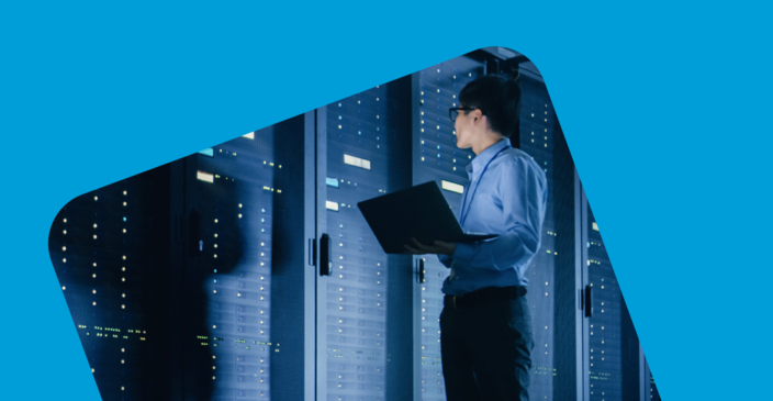 Man walking around working on a laptop in a server room